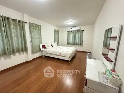 Spacious bedroom with wooden flooring and elegant decor