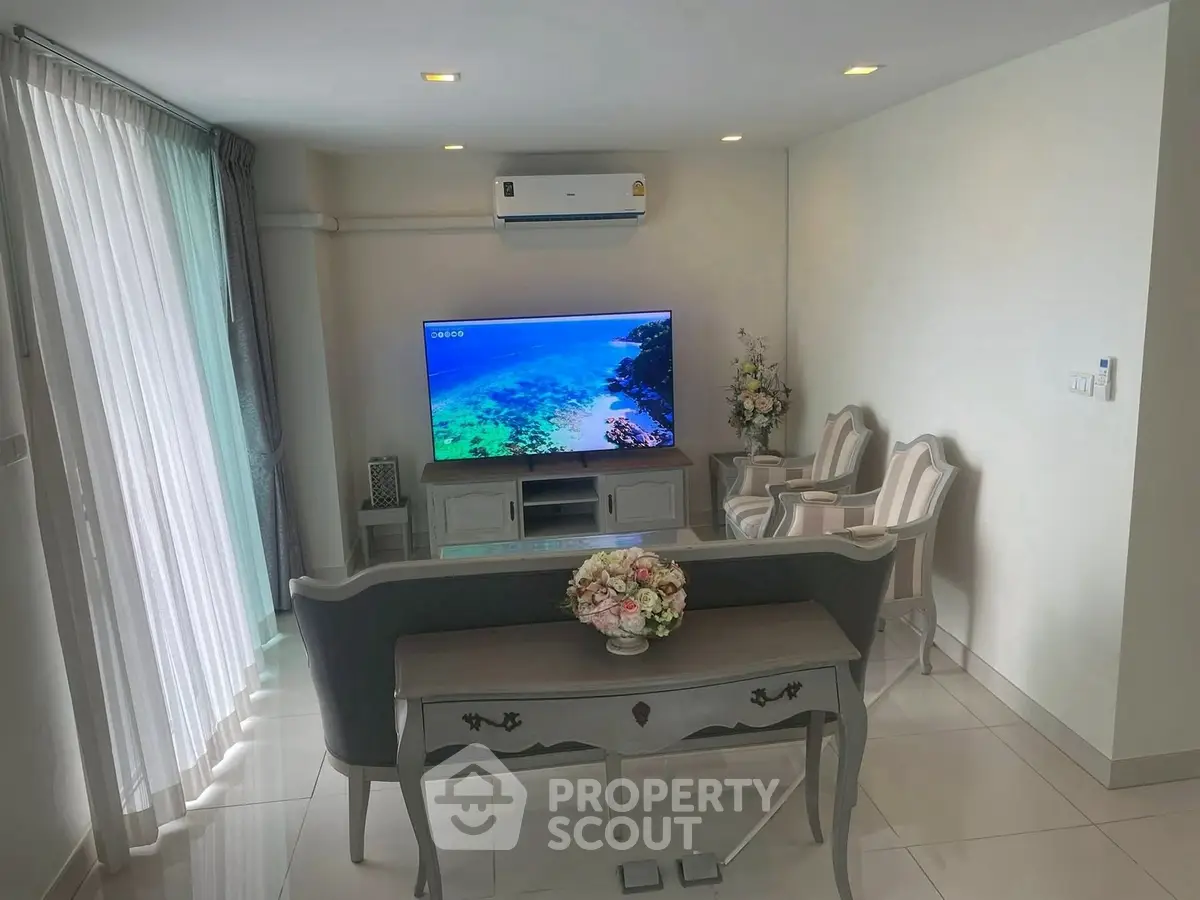 Elegant living room with modern decor and large TV, perfect for relaxation.