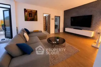 Spacious modern living room with stylish decor and large TV, perfect for relaxation.