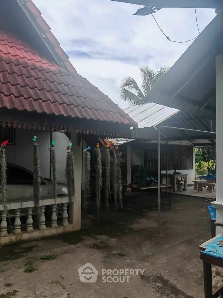 Charming traditional house exterior with rustic roof and open outdoor space, perfect for tropical living.