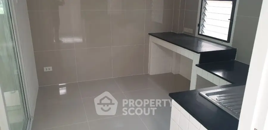 Modern kitchen with sleek countertops and tiled walls, featuring a compact and efficient layout.