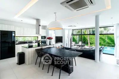 Luxurious open-plan kitchen and living area with pool view, modern appliances, and elegant decor.