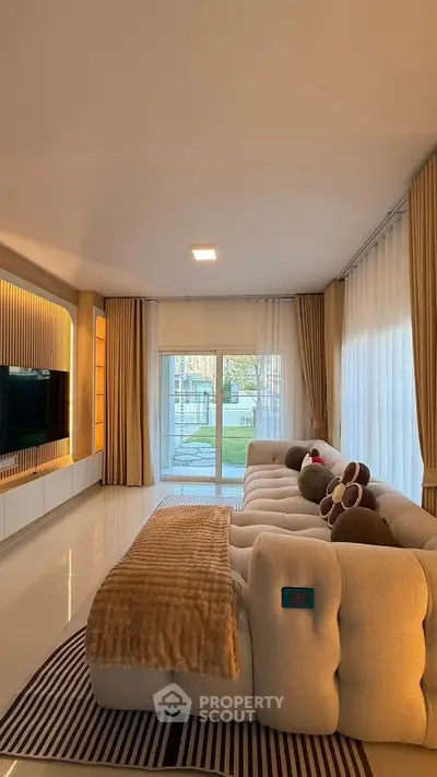 Luxurious living room with plush sofa and large windows overlooking a serene garden view.