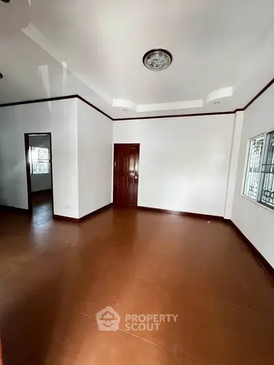 Spacious empty room with brown flooring and white walls, ideal for customization.