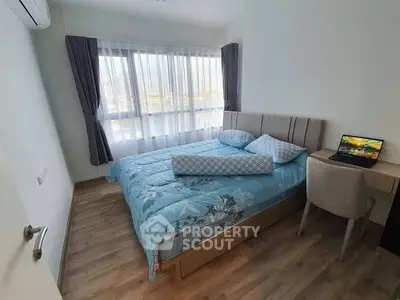 Cozy bedroom with modern decor and natural light from large window, perfect for relaxation.