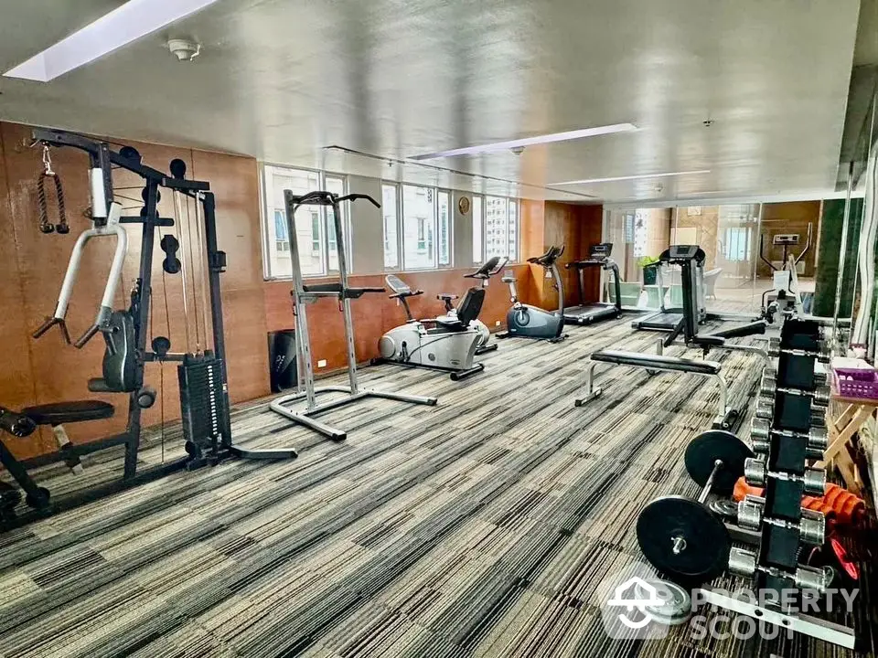 Spacious modern gym with state-of-the-art equipment and large windows for natural light.