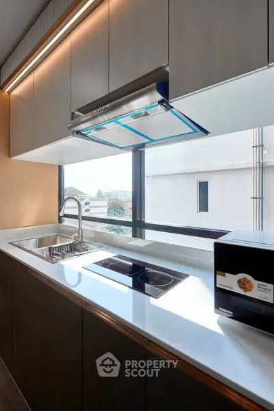 Modern kitchen with sleek countertops and built-in appliances, featuring a large window with a view.