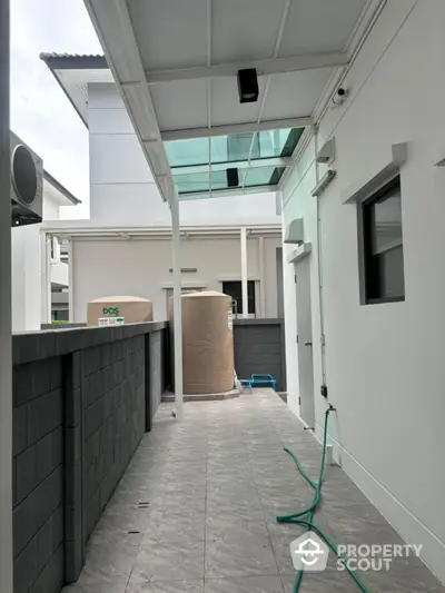 Modern exterior corridor with sleek design and water tank, ideal for contemporary homes.