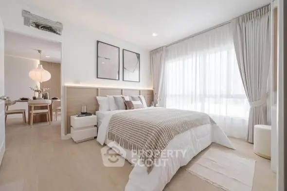 Elegant bedroom with modern decor and natural light, featuring cozy bedding and stylish artwork.