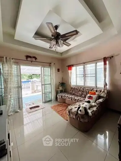 Spacious living room with modern ceiling fan and large windows opening to a balcony.