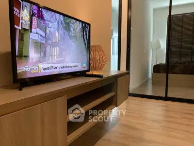 Modern living room with wooden flooring and stylish TV stand, featuring a cozy ambiance.