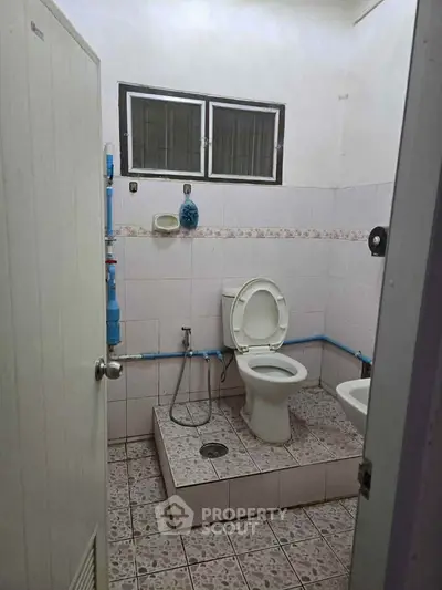 Simple bathroom with tiled floor and basic fixtures in a residential property.