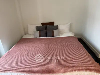 Cozy bedroom with stylish bedding and decorative pillows in a modern apartment.