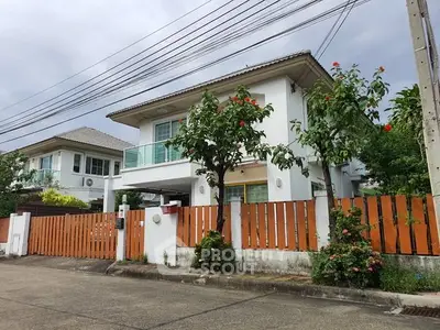 Charming two-story house with lush garden and wooden fence in a serene neighborhood.