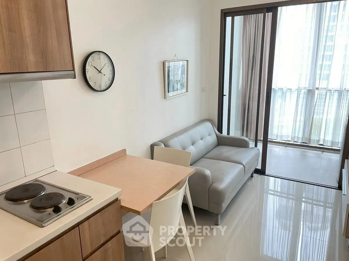 Modern apartment with sleek kitchen and cozy living area, featuring large windows for natural light.