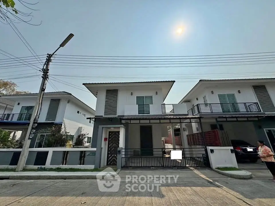 Modern two-story houses with balconies and driveway in a suburban neighborhood.