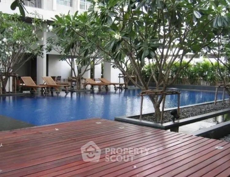 Luxurious poolside area with wooden deck and lush greenery