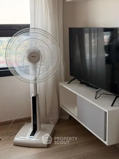 Modern living room with sleek TV stand and standing fan by window