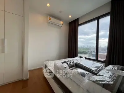 Modern bedroom with city view, featuring large window and air conditioning.