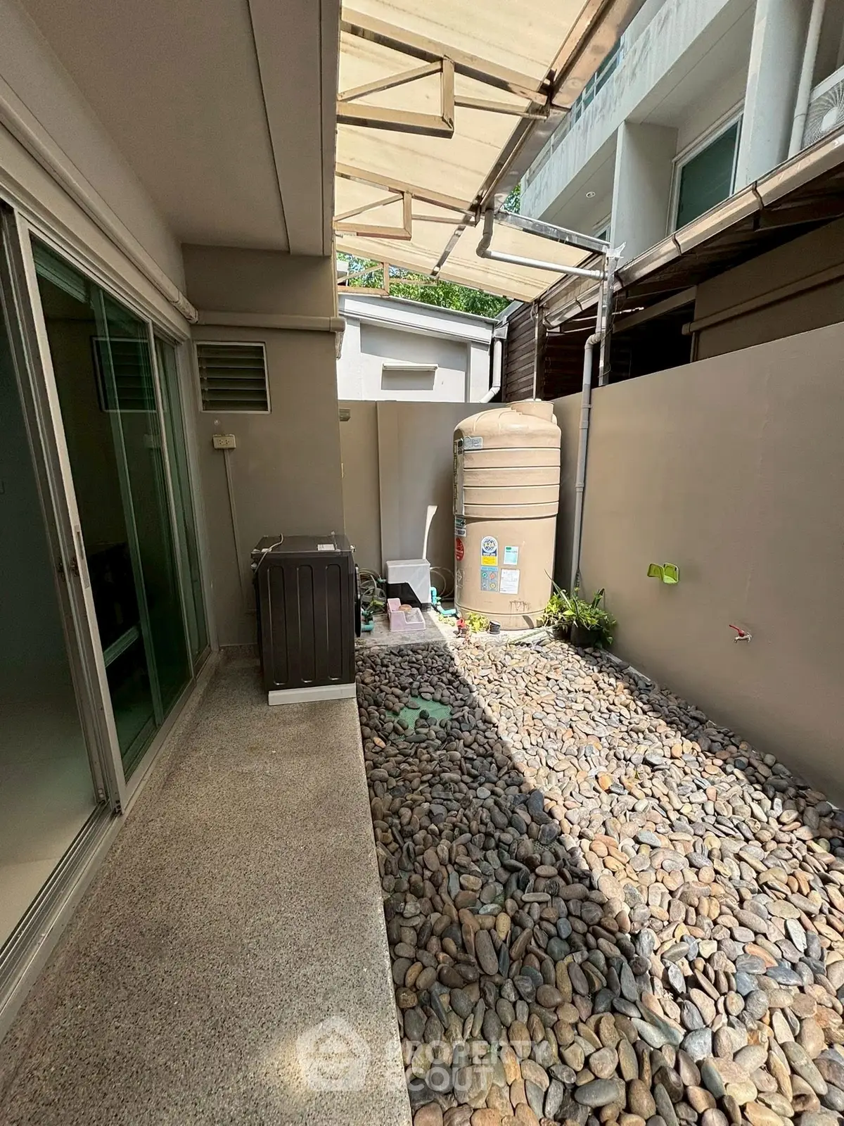 Charming outdoor area with pebble flooring and modern amenities, perfect for relaxation and utility.