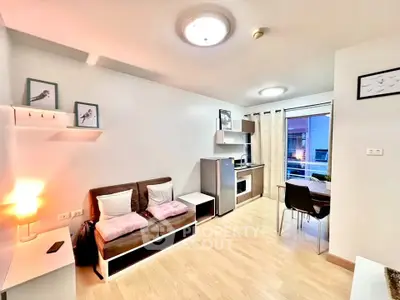 Modern living room with kitchenette and dining area, featuring cozy decor and natural light.