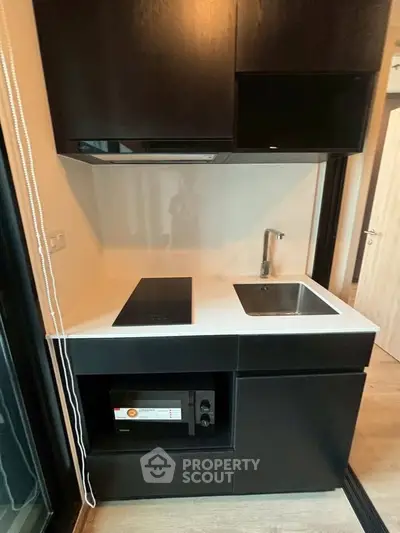Modern compact kitchen with sleek black cabinetry and built-in appliances