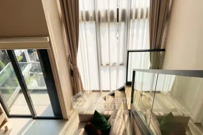Luxurious loft-style living room with floor-to-ceiling windows and balcony access