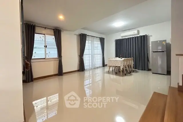 Spacious modern living room with dining area and large windows, featuring sleek flooring and contemporary decor.