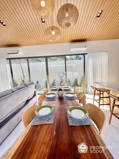 Elegant dining area with wooden table and modern decor, featuring large windows and stylish lighting.