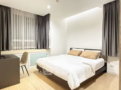 Modern bedroom with cozy bed, study desk, and elegant curtains in a bright apartment.