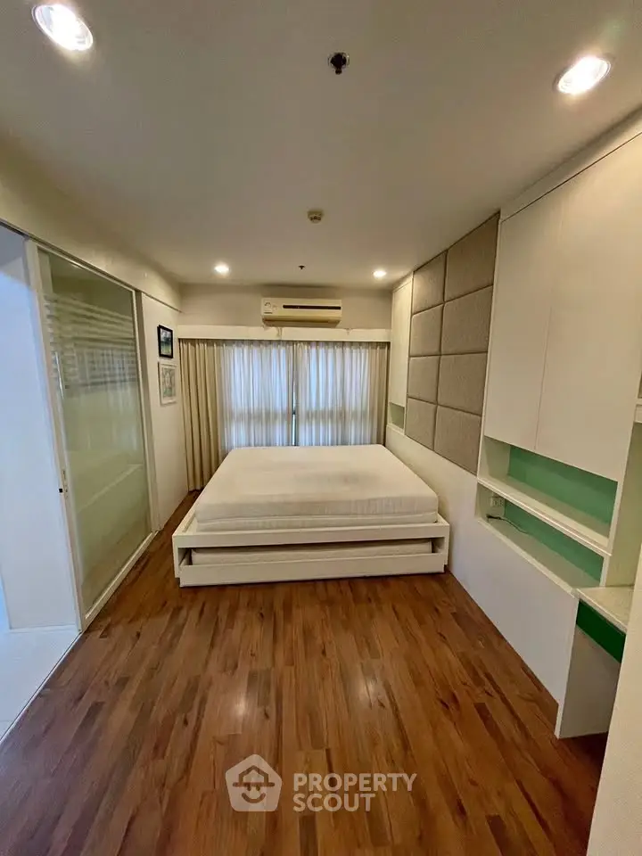 Spacious bedroom with modern design, featuring wooden flooring and ample natural light.