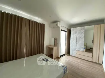 Spacious bedroom with modern furnishings and large window for natural light.