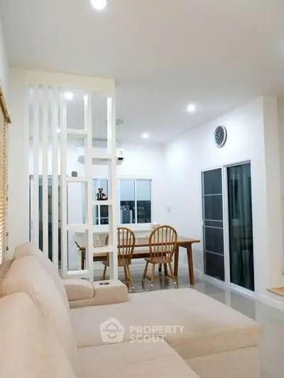 Spacious living room with modern decor and dining area, featuring elegant furniture and bright lighting.