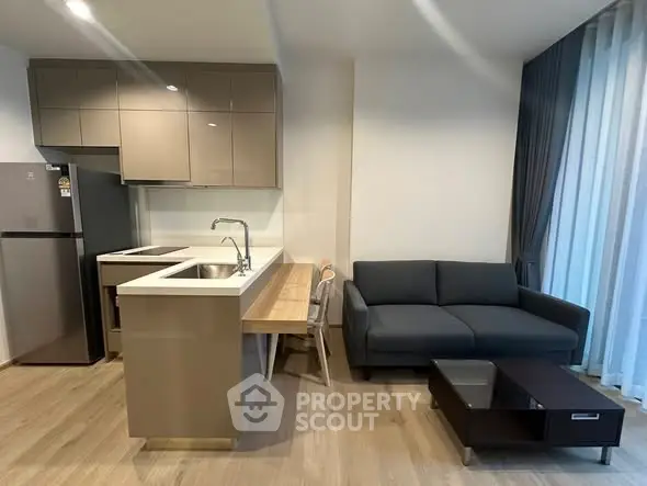 Modern open-layout kitchen and living room with sleek furniture and natural light.