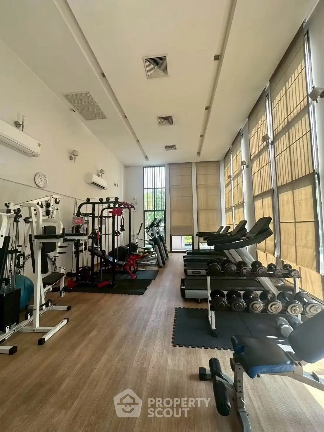 Spacious gym with modern equipment and large windows in a residential building.