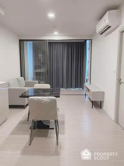 Modern living room with sleek furniture and ample lighting, featuring a large window with dark curtains and a pristine tiled floor.