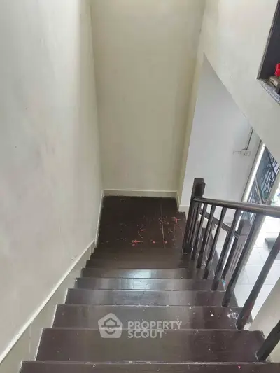 Wooden staircase with dark finish leading to a bright hallway in a residential property.