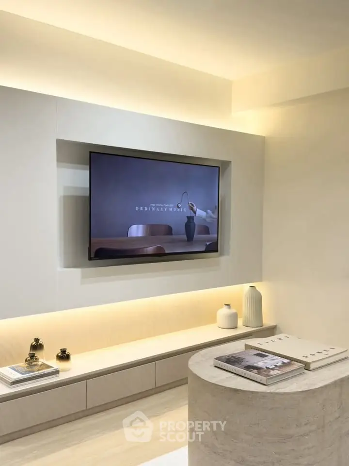 Modern living room with built-in TV and stylish decor, featuring soft lighting and contemporary design.