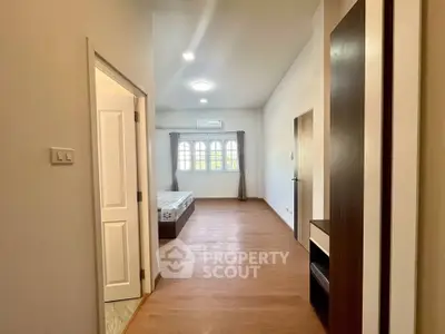 Spacious bedroom with wooden flooring and natural light, featuring a cozy bed and modern design.