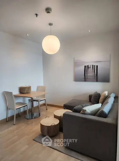 Modern living room with cozy sofa and dining area, featuring minimalist decor and soft lighting.