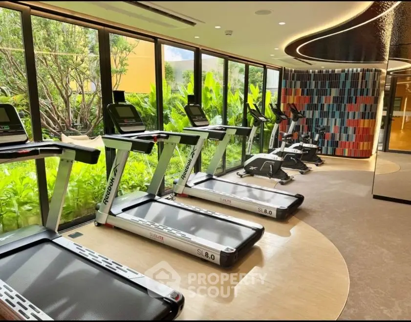 Modern gym with treadmills and vibrant decor overlooking lush greenery.