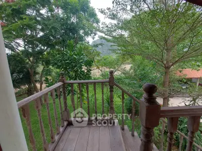 Charming wooden balcony with lush green garden view, perfect for relaxation and nature lovers.