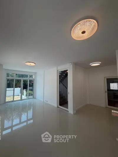 Spacious modern living room with elegant lighting and large windows overlooking a garden.