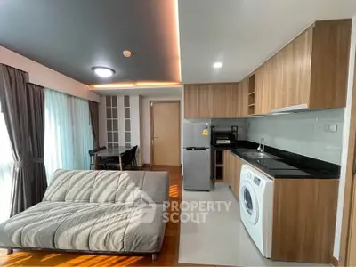 Modern open-layout living room with kitchen, featuring sleek furniture and appliances, ideal for urban living.