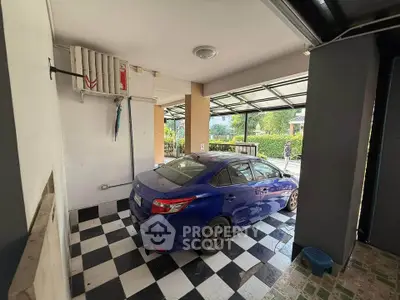 Spacious garage with checkered flooring and parked blue car in modern home.
