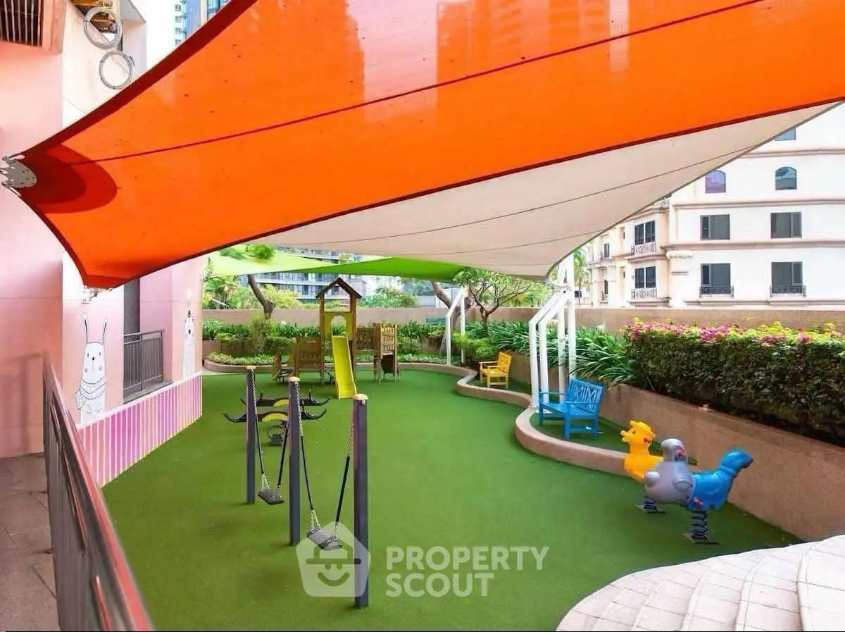 Vibrant children's playground in a modern residential complex with colorful shade sails and play equipment.
