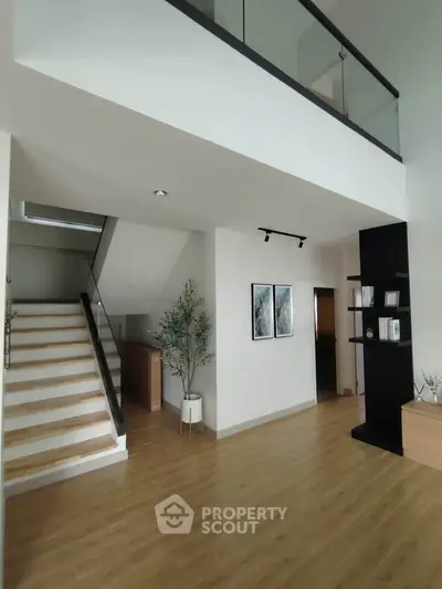 Spacious modern living area with wooden flooring and stylish staircase