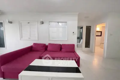 Modern living room with vibrant pink sofa and sleek white decor