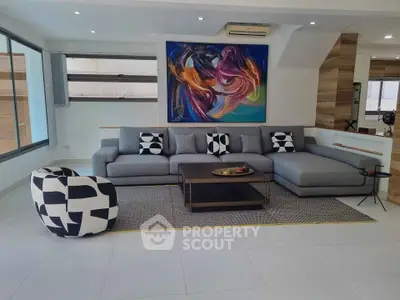 Modern living room with stylish gray sectional sofa and abstract art on the wall