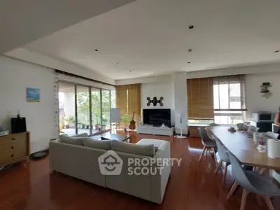 Spacious living room with modern decor and large windows opening to a balcony.